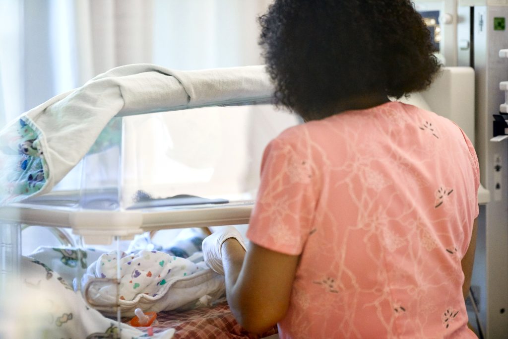 Baby in the Children's Minnesota NICU with a health care provider helping.