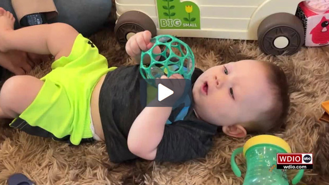 Baby Bennett laying on floor playing with a toy