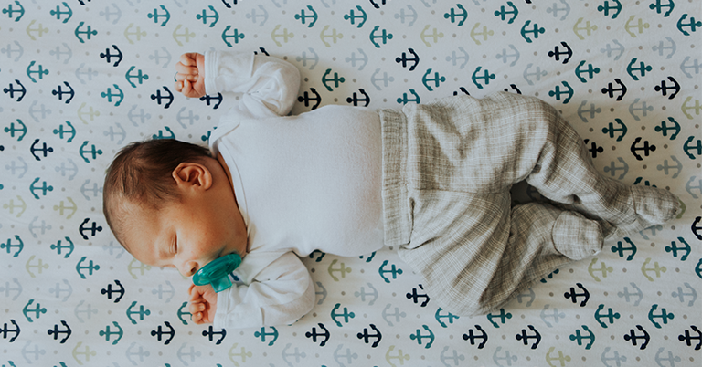 Newborn adorably sleeping in his safe baby crib, following crib safety standards and guidelines on how to make a crib safe for babies, promoting safety and secure sleeping environments.