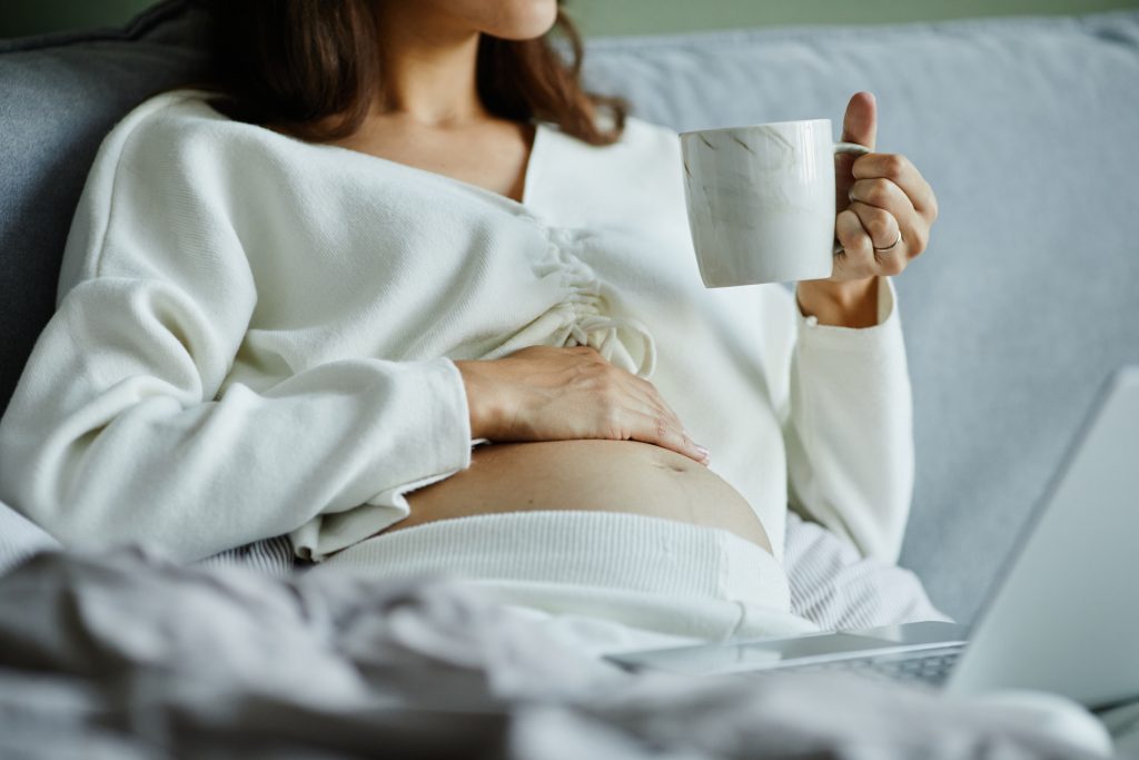 Pregnant woman drinking tea in bed