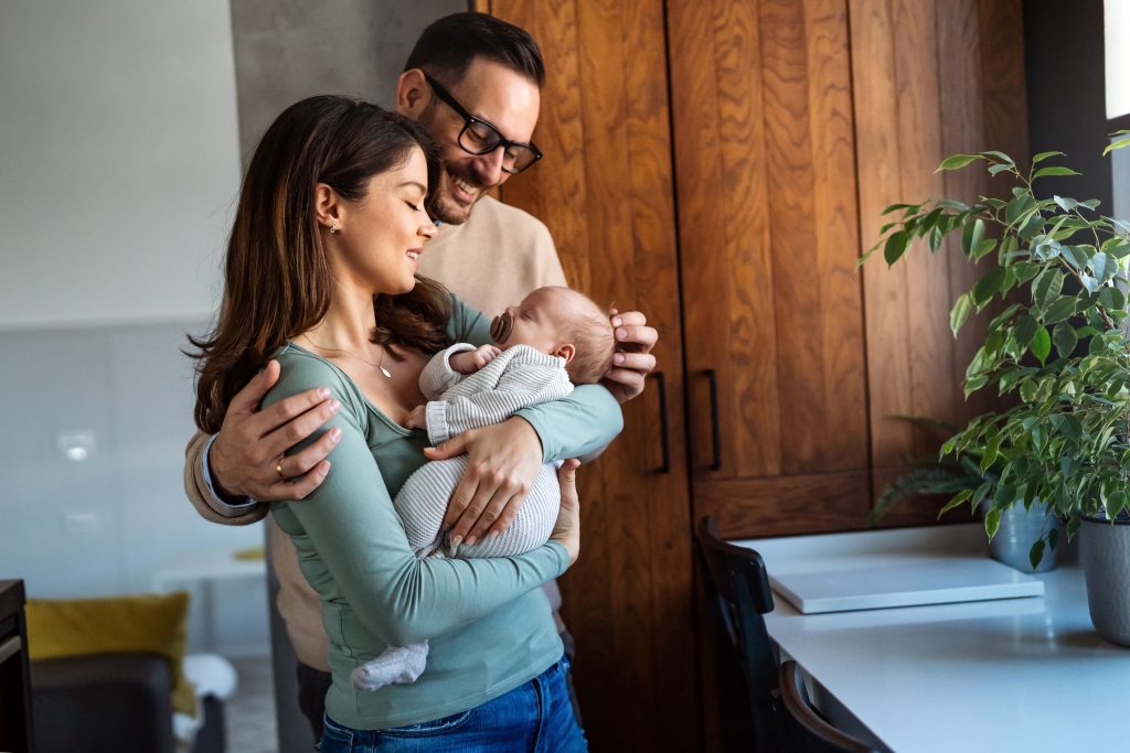 Portrait of young happy man and woman holding newborn cute babe