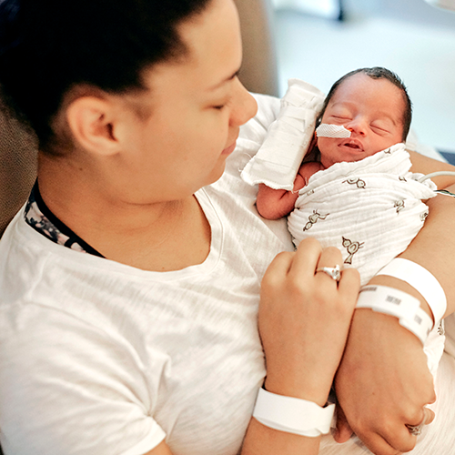 New mom holding her newborn baby in the Children's Minnesota NICU